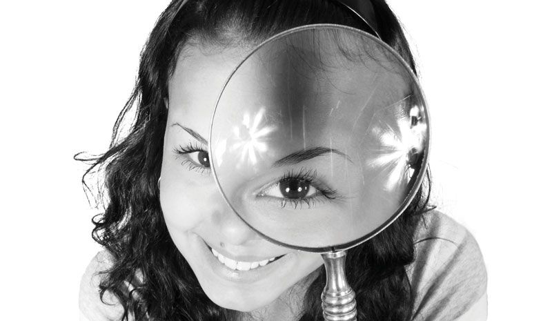 Photo of ladies head with magnifying glass in front of one eye making it look big.
